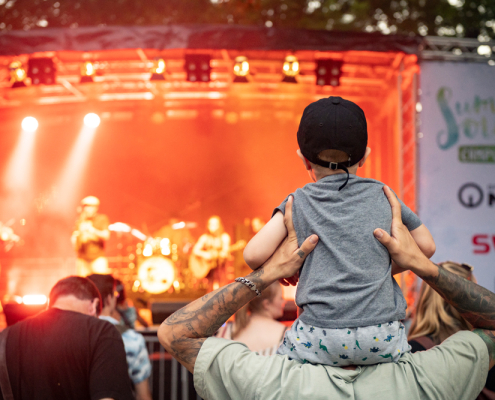 Kind auf den Schultern eines Erwachsenen beim Konzert